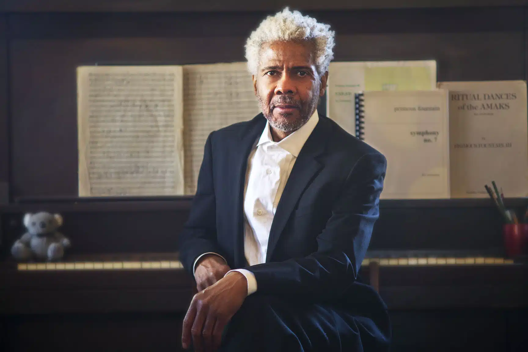 Primous Fountain seated at a piano with his orchestral scores